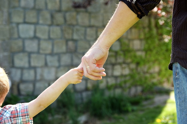 Der Elternteil hält die Hand eines kleinen Kindes auf der Natur