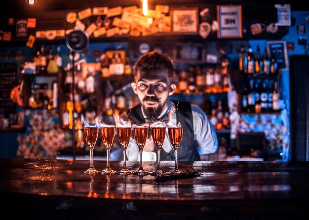 Der erfahrene Barkeeper beendet seine Kreation intensiv, während er in der Nähe der Theke im Nachtclub steht