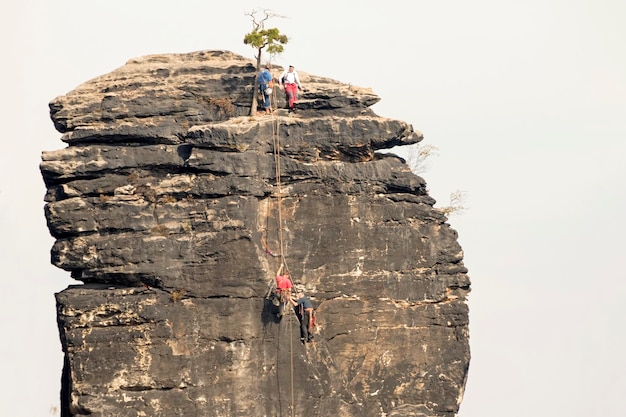 Der Felsen gegen den Himmel mit den Kletterern an der Oberfläche