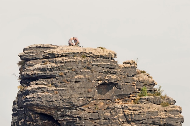 Der Felsen gegen den Himmel mit den Kletterern an der Oberfläche