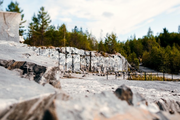 Der Felsen hat eine unbehandelte Oberfläche aus weißem und grauem Marmor in eine natürliche Umgebung gehauen. Die Steinbruchstruktur aus blauem Marmor.