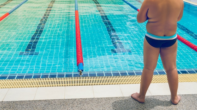 Foto der fette jungenstudent, der bereit ist, übung für gewicht für gesundes zu schwimmen zu schwimmen.