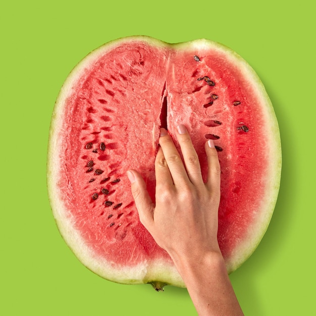 Der Finger der Frau berührt die reife saftige Frucht der Wassermelone