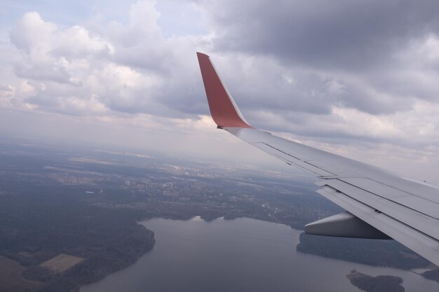 Der Flügel eines fliegenden Flugzeugs vor dem Hintergrund von Wolken