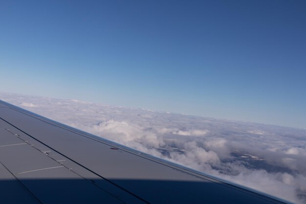 Der Flügel eines fliegenden Flugzeugs vor dem Hintergrund von Wolken