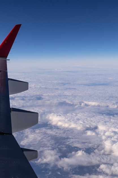 Der Flügel eines fliegenden Flugzeugs vor dem Hintergrund von Wolken