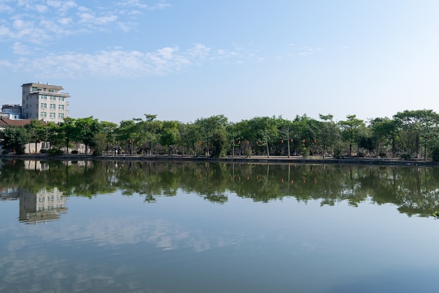 Der Fluss spiegelt die schöne Landschaft auf beiden Seiten mit grünen Bäumen und Häusern wider.