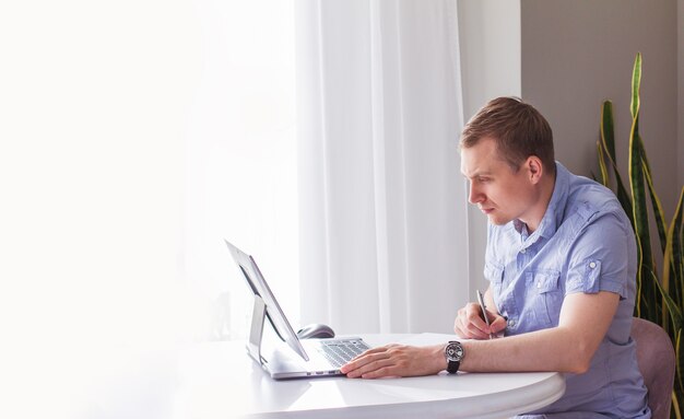 Der fokussierte junge europäische Geschäftsmann arbeitet zu Hause mit einem Laptop