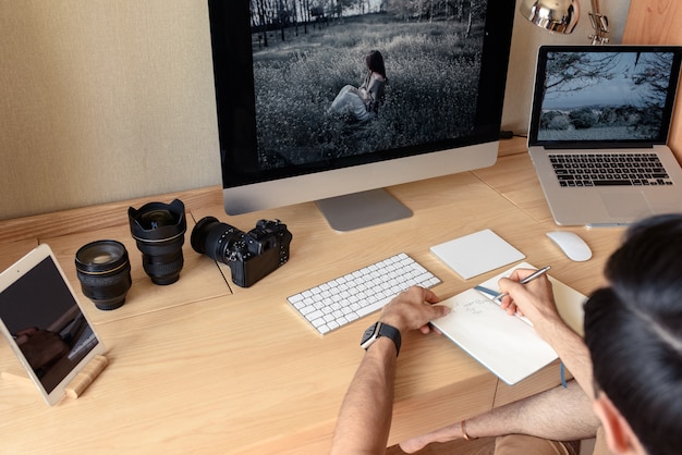 Der Fotograf sitzt an einem Tisch und schreibt in ein Notizbuch