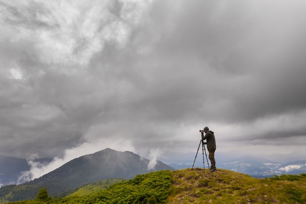 Der Fotograf steht auf dem Berg mit Regenwolken