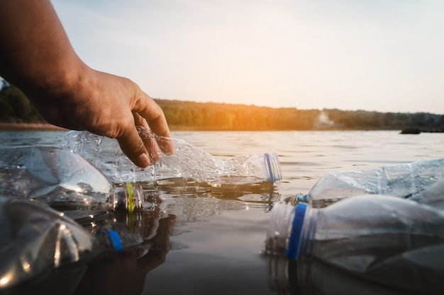 Der Freiwillige, der einen Flaschenplastik im Fluss aufhebt, schützt Umwelt vor einem Verschmutzungskonzept.