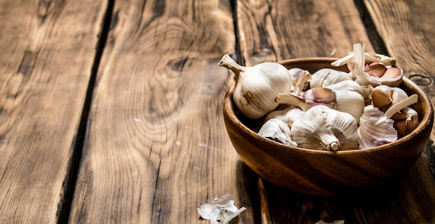 Der frische Knoblauch in einer Holzschale. Auf hölzernem Hintergrund.