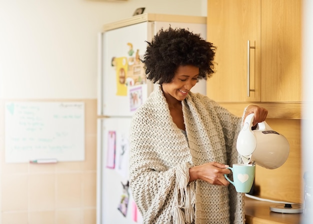 Der frischeste Start in den Tag Aufnahme einer jungen Frau, die sich morgens zu Hause eine Tasse Tee kocht