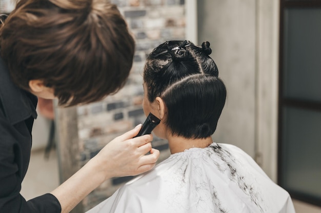 Der Friseur glättet die Haare des Mädchens nach einem kurzen Haarschnitt