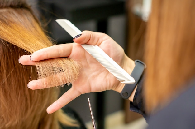 Der Friseur schneidet der jungen Frau im Schönheitssalon braune Haare