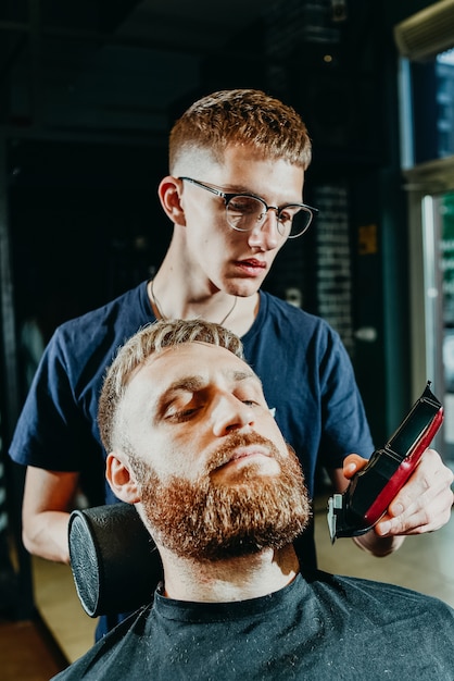 Der Friseur schneidet einem Mann im Salon den Bart