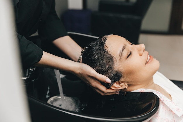 Der Friseur wäscht den Kopf eines Mädchens in einem Friseurladen. Eine Brünette kam zum Haareschneiden