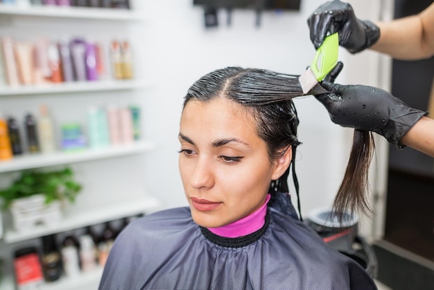 Der Friseur wendet professionelles flüssiges Keratin auf das Haar des Kunden an Ein Mädchen macht Keratin-Haarstärkung in einem Schönheitssalon Haarpflege