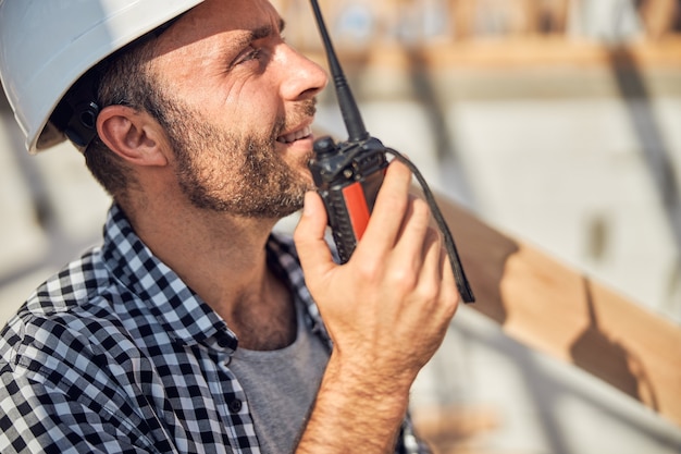 Der fröhliche Baumeister hält ein Walkietalkie nah an seinem Mund