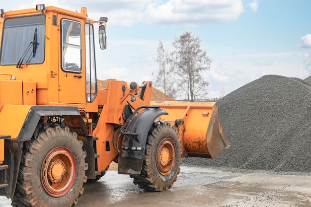 Der Frontlader nimmt Kies oder Schotter in der Frontschaufel auf Schwere Baumaschinen auf der Baustelle Materialtransport in einem Betonwerk