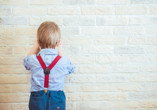 Der frustrierte kleine junge, der in der nähe der wand stand, wandte sich ab