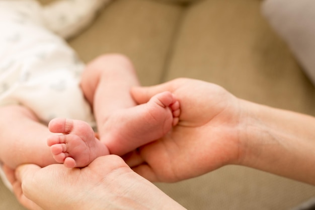 Der Fuß eines Babys wird von einer Frau hochgehalten