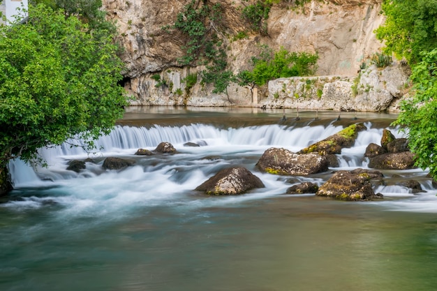 Der Gebirgsfluss bildete einen kleinen Wasserfall zwischen den steinigen Stromschnellen.