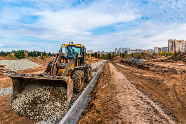 Der gelbe Traktor richtet die Steine für die neue Straße aus