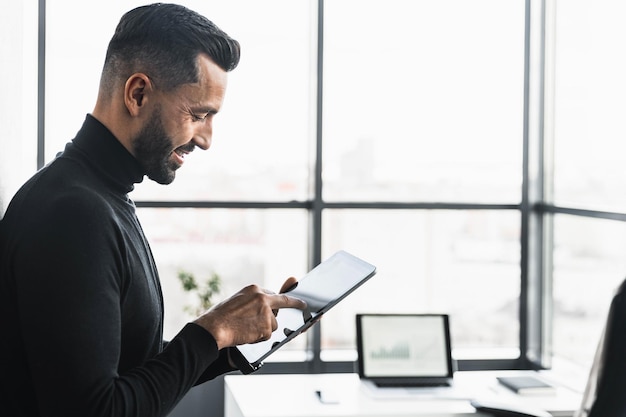 Der Geschäftsmann arbeitet im Büro an einem Tablet