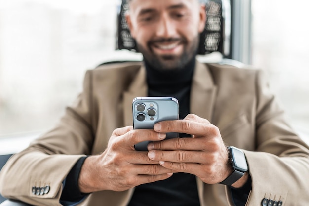 Der Geschäftsmann benutzt ein Mobiltelefon, das es aus nächster Nähe in seinen Händen hält