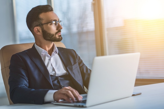 Der Geschäftsmann mit Brille, der mit einem Laptop arbeitet