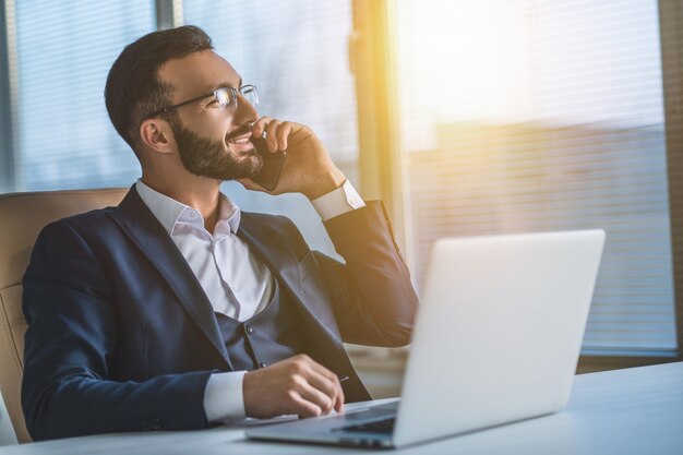 Der Geschäftsmann mit Brille, der mit einem Laptop arbeitet