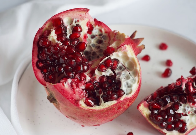 Der geschnittene Granatapfel liegt auf einem weißen Teller. Dahinter liegt ein weißes Handtuch