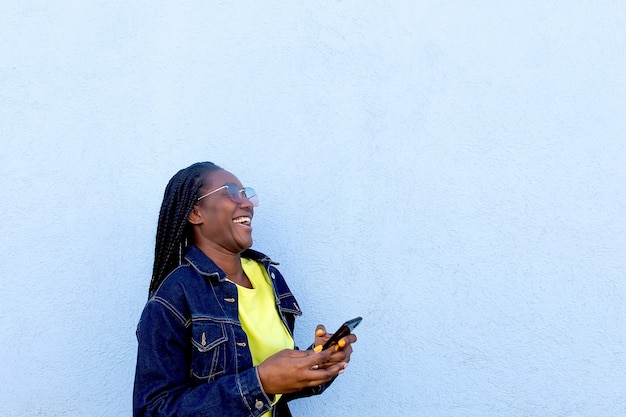 Der glückliche Afroamerikaner mit Telefon auf blauem Hintergrund