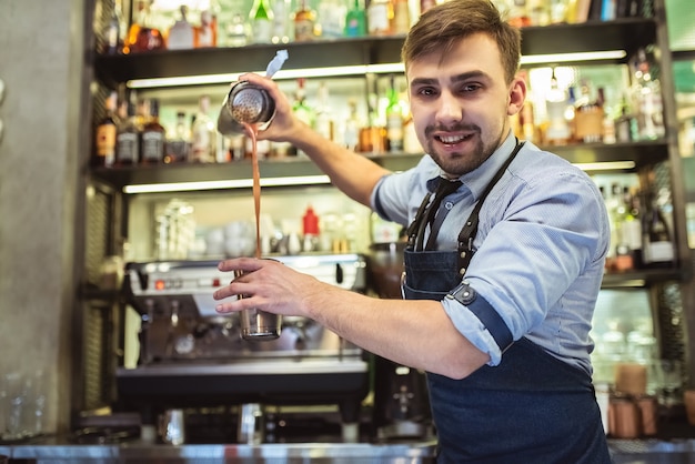 Der glückliche Barkeeper, der an der Bar arbeitet