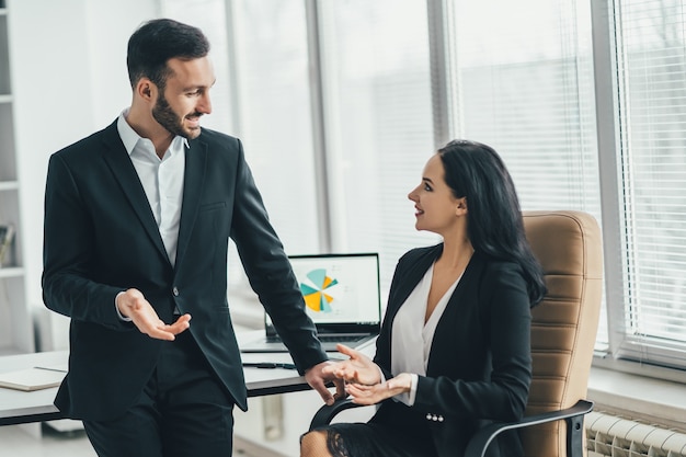 Der glückliche Geschäftsmann und eine Frau, die nahe dem Bürotisch sprechen