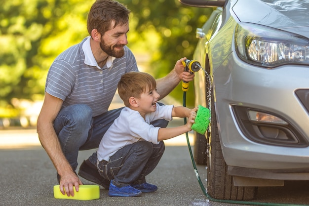 Foto der glückliche junge und ein vater, der ein auto wäscht