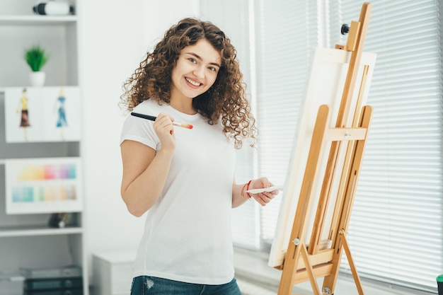 Der glückliche Künstler malt ein Bild auf der Staffelei