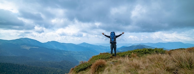 Der glückliche Mann, der auf dem Berg auf dem regnerischen Wolkenhintergrund steht