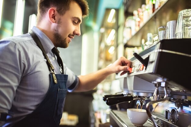 Der glückliche Mann, der einen Kaffee an der Bar kocht