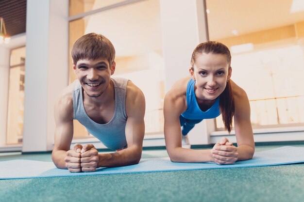 Der glückliche Mann und die Frau, die Sport tut, stehen auf Matte