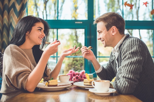 Der glückliche Mann und die glückliche Frau, die im Café einen Kuchen essen