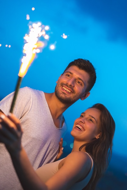 Der glückliche Mann und die glückliche Frau halten einen Feuerwerksstock. abend nacht zeit