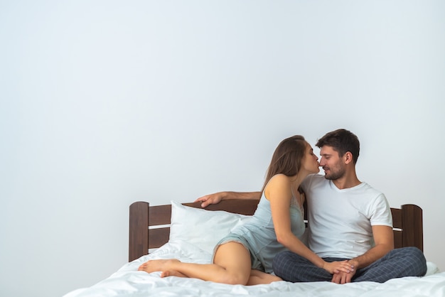 Der glückliche Mann und eine Frau, die sich auf dem Bett küssen