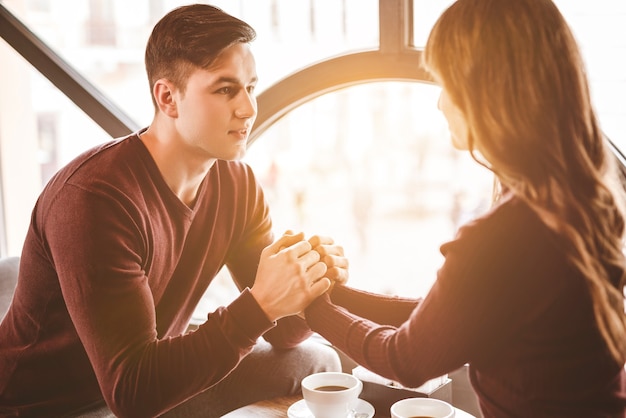 Der glückliche Mann und eine Frau halten Händchen am Tisch im Restaurant