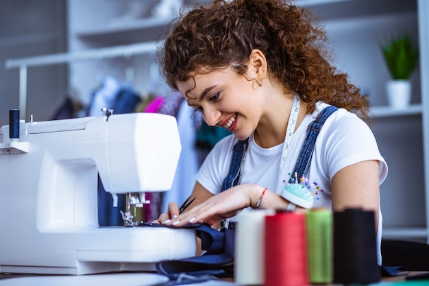 Der glückliche Schneider, der in der Nähe der Nähmaschine arbeitet