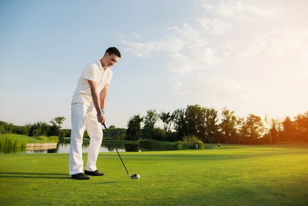 Der Golfspieler, der Schuss-Ball nimmt, ist auf dem T-Stück.