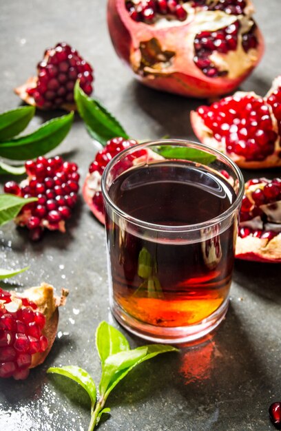 Der Granatapfelsaft in einem Glas mit Granatapfelstücken und Blättern