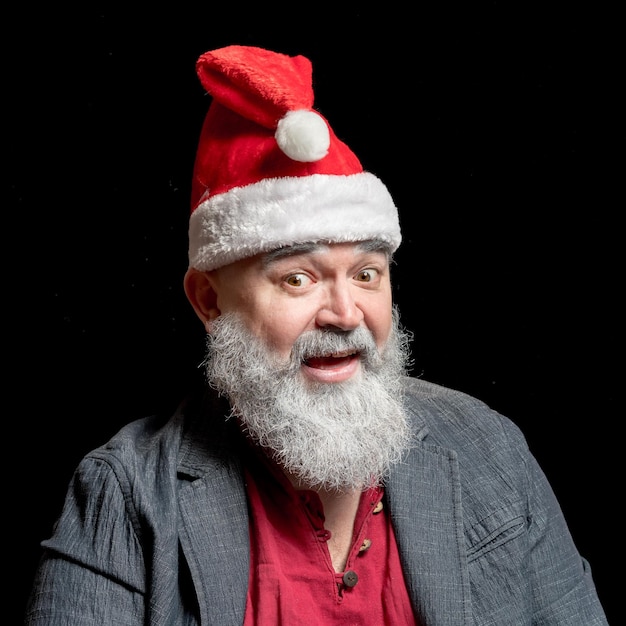 Der graubärtige fröhliche alte Mann mit Weihnachtsmannmütze