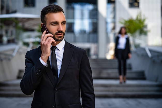 Der gutaussehende Mann im Anzug telefoniert in der Nähe des Geschäftszentrums